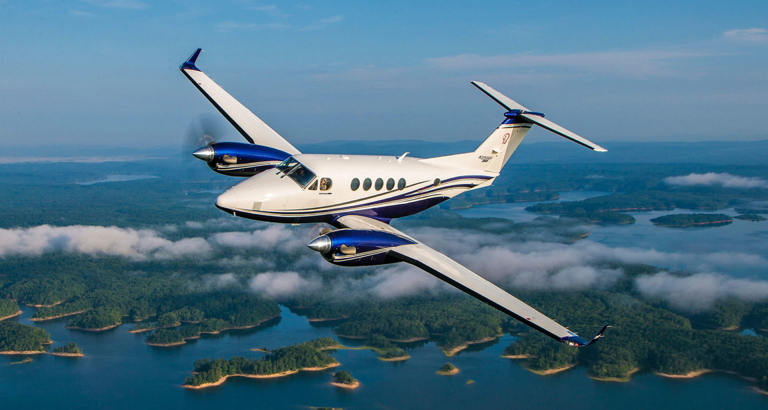 Private jet flying over a landscape with lakes and forests