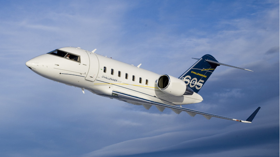 Private jet flying against a blue sky with some clouds